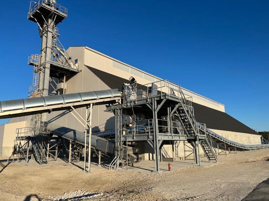 Bulk storage facility and conveying equipment located on a river for barge receiving