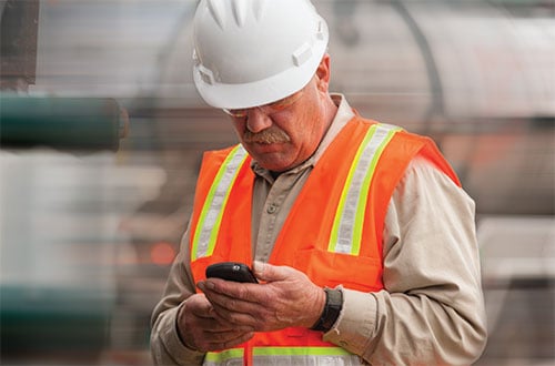 Construction workers using cell phone with safety vest and hard hat